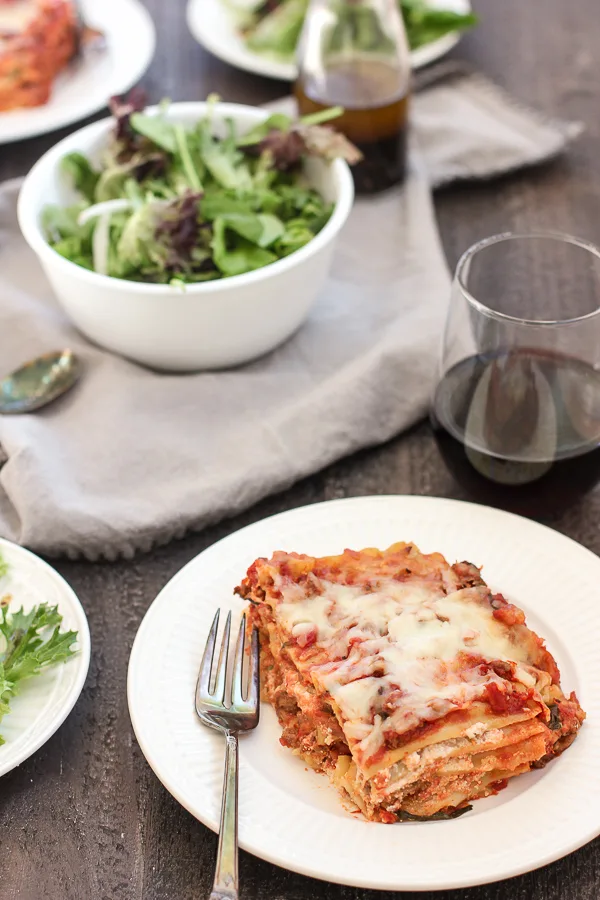 Plated lasagna with salad and wine