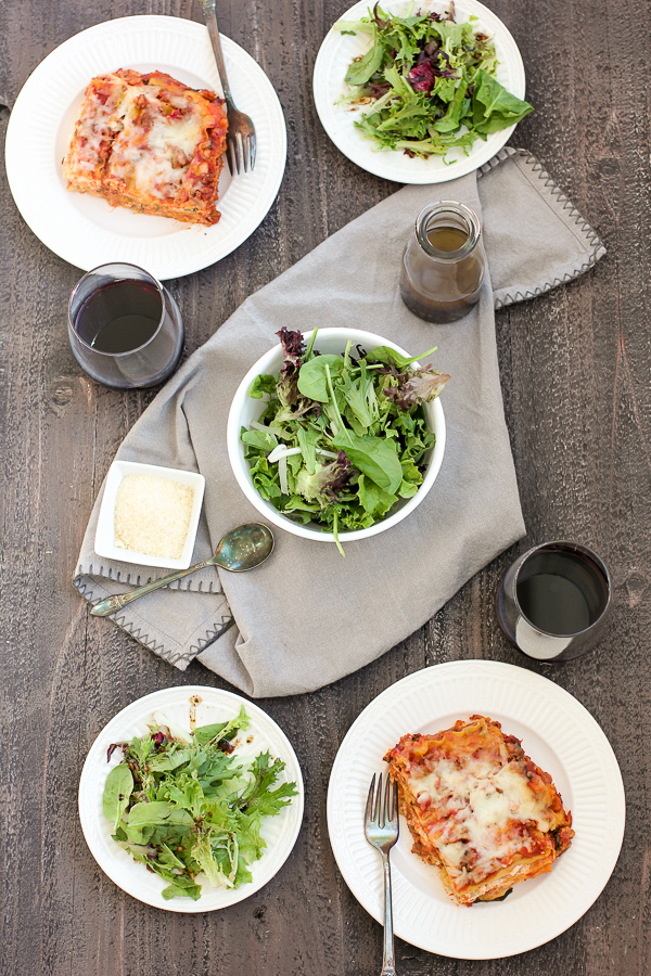 Photo of lasagne plated with salad and wine