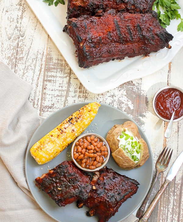 Finished ribs served with corn on the cob, baked beans and baked potato