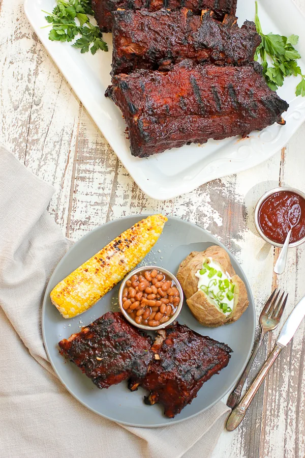 Finished ribs served with corn on the cob, baked beans and baked potato