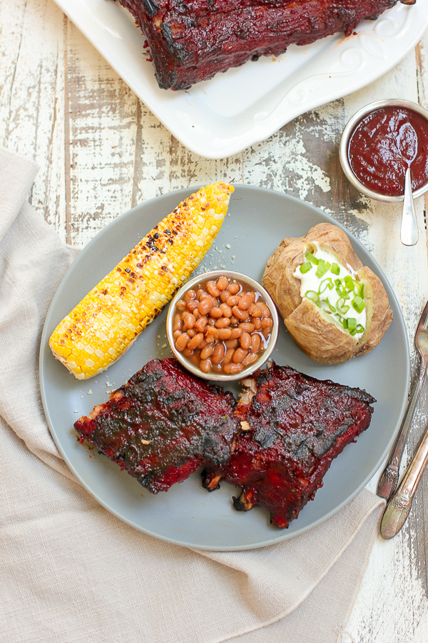 Showing the baby back ribs finished and plated with corn on the cob, baked potato and baked beans.