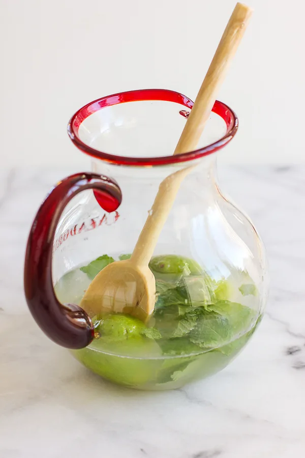 Demonstrating how to muddle the lime and the mint with a wooden spoon