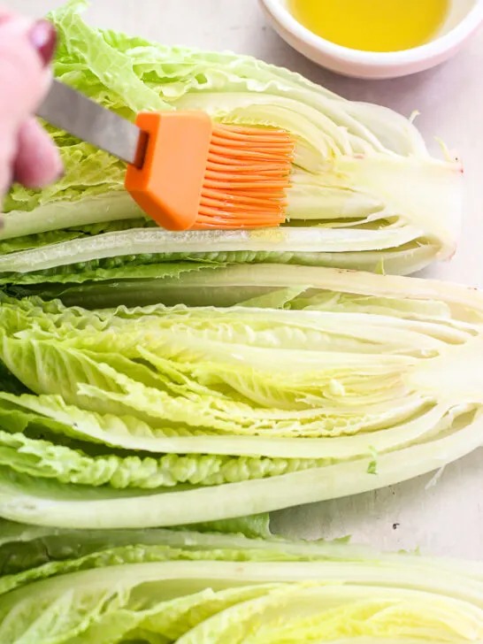 Demonstrating brushing the olive oil on the cut side of the romaine