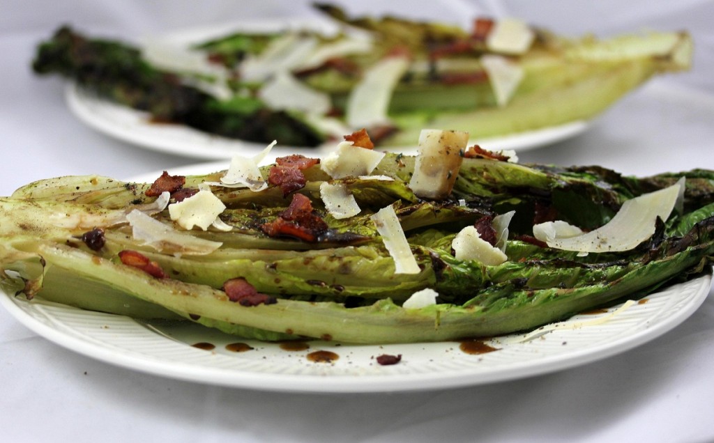 closeup of plate of grilled romaine topped with cheese and bacon