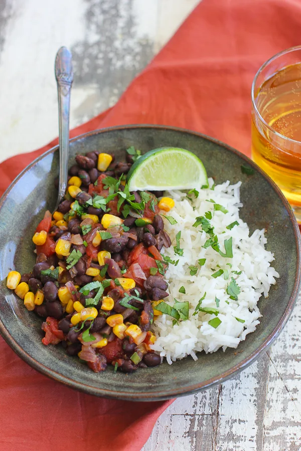 beans and rice served in a bowl garnished with lime and cilantro