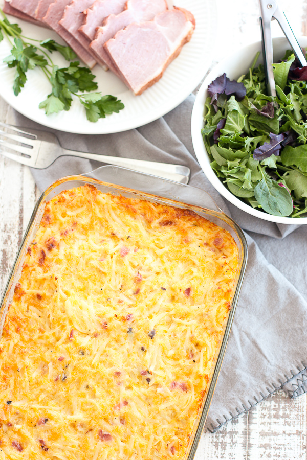Finished cheesy hash brown casserole shown with ham and salad