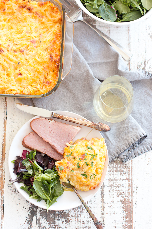 Finished pan of cheesy hash browns along with the hash browns plated with ham, salad and white wine