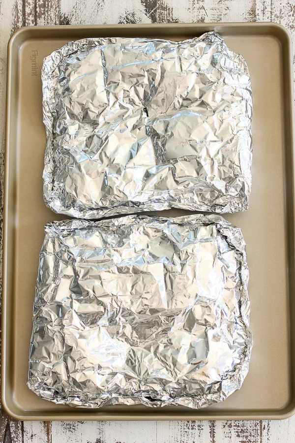 The foil packets of potatoes on a sheet pan ready for the grill