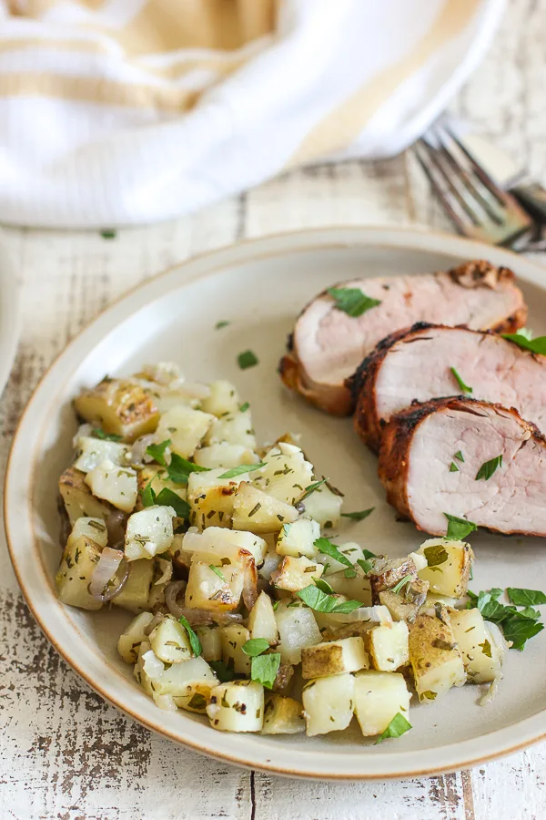 Grill potatoes served with grilled pork tenderloin on a plate.