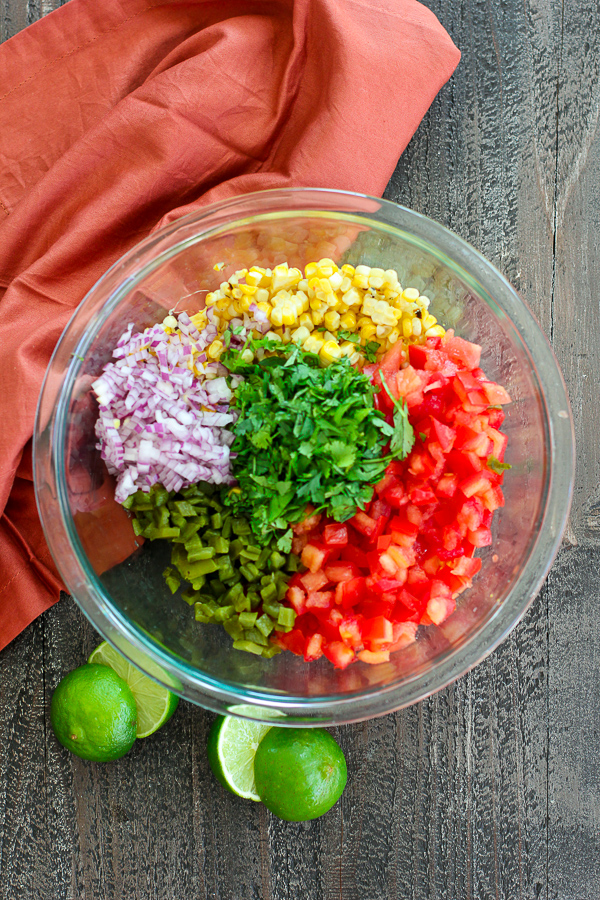 Grilled corn and jalapeno salsa ingredients in a bowl before mixing them together