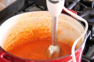pureeing the tomatoes in the pot with an immersion blender