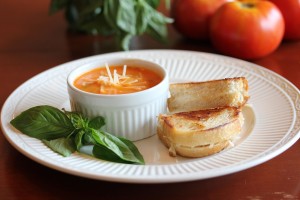 soup in a bowl and grilled cheese dippers plated together with a garnish of basil