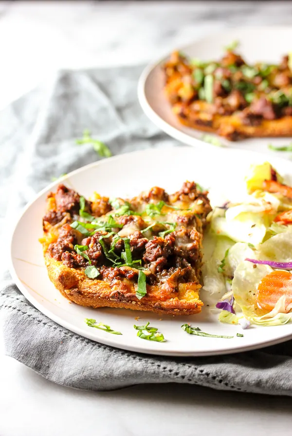 Close up of a slice of Easy Deep Dish Pizza Casserole serve on a plate with a salad