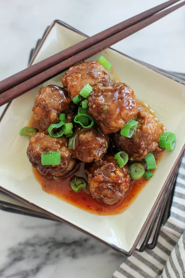 Shot of plated meatballs, garnished with sliced green onion