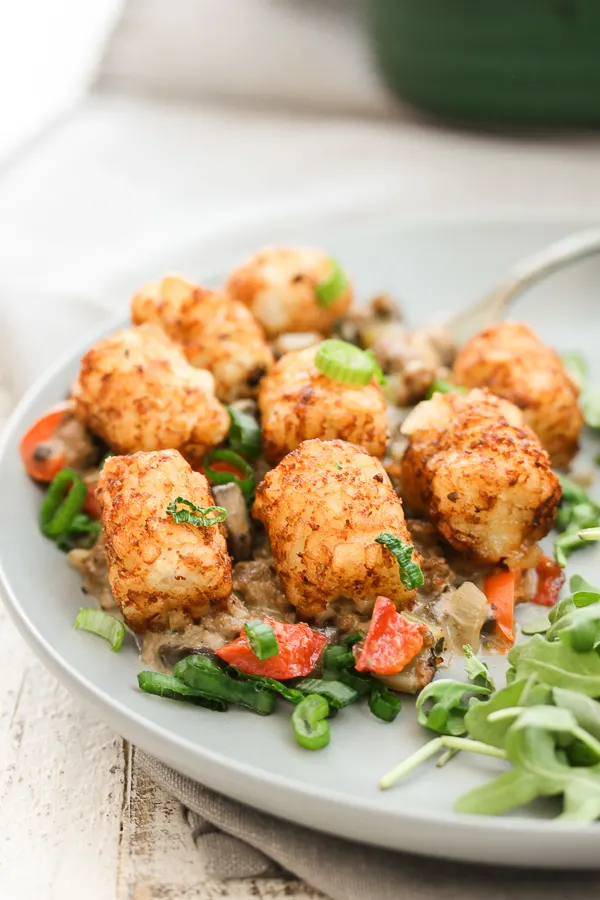 Close up of A Healthier Tator Tot Casserole plated with arugula on the side