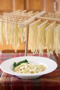 Pasta on a drying rack and cooked pasta in a bowl