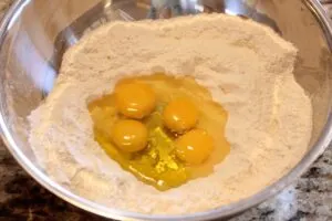 Flour in the bowl with a well filled with eggs
