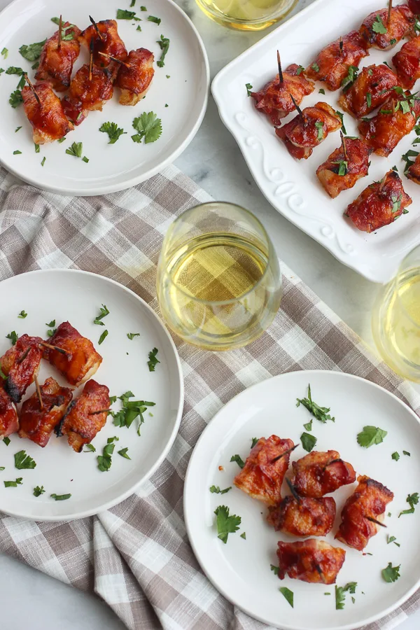 BBQ Bacon Wrapped Water Chestnuts on appetizer plated served with white wine.