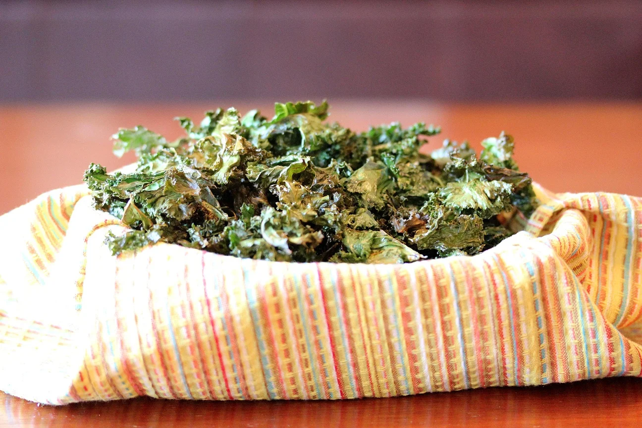 crispy garlic kale chips served in a bowl lined with a napkin