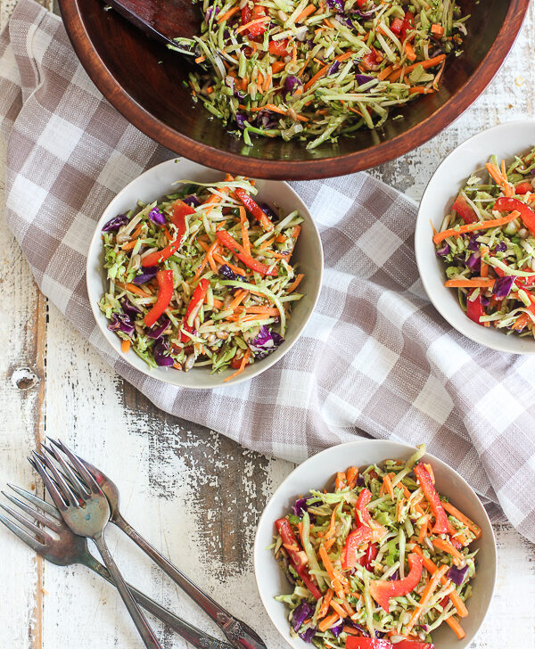 Asian Broccoli Slaw in a wooden serving bowl shown serve in small bowls