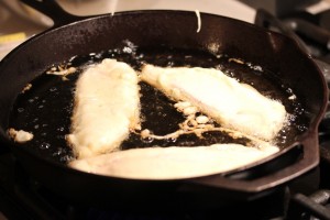 beer battered fish in the cast iron skillet shallow frying on the first side