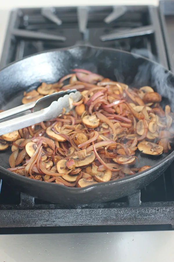 Onions and mushrooms sautéing in a cast iron skillet