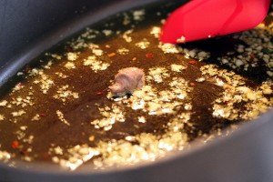 Anchovy paste and garlic sautéing in the pan