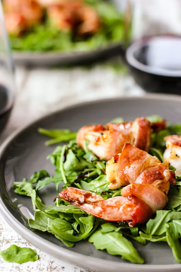 Close up photo of Bacon Wrapped Shrimp plated with arugula
