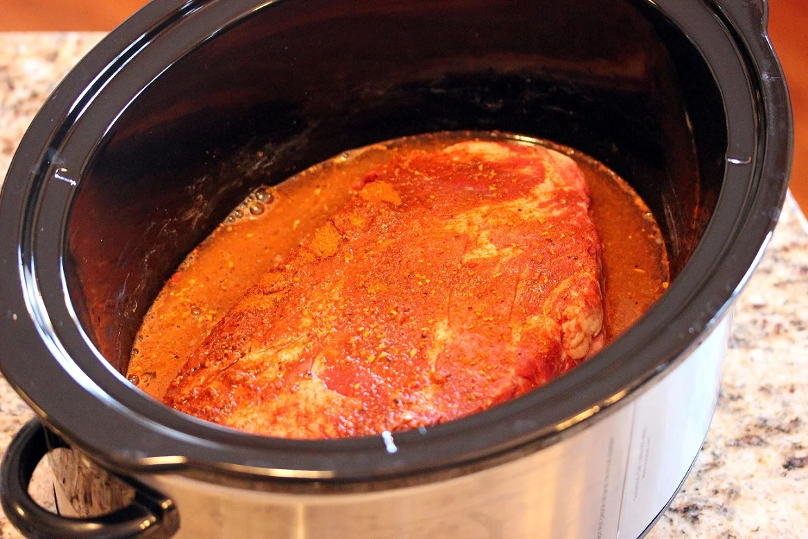 chuck roast in the slow cooker with the taco seasoning and liquid before cooking