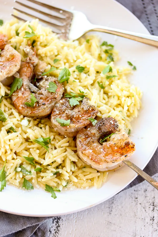 Close up showing the shrimp skewer served on top of the orzo