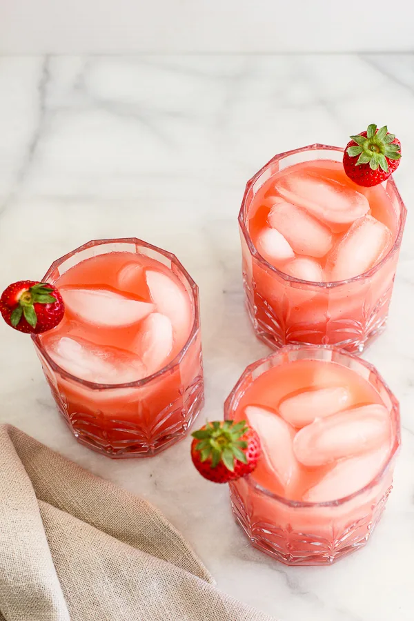 Overhead photo showing mixed margaritas in three glasses garnished with a fresh strawberry