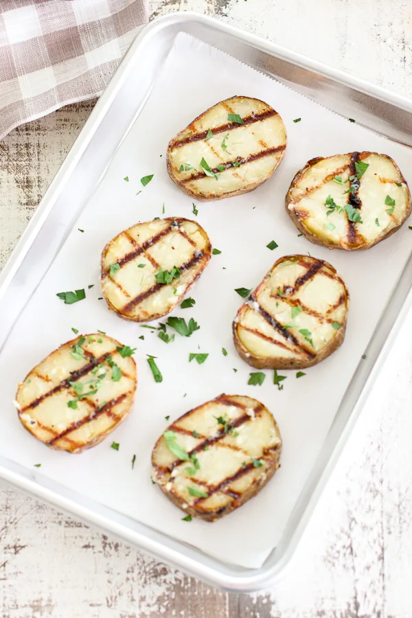 Grilled potato slices plated on a sheet pan