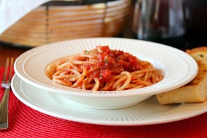 Bucatini all'amatriciana served in a bowl with bread and salad