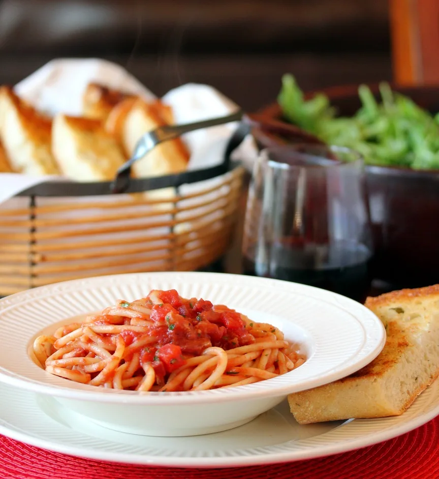 Bucatini all'amatriciana all finished and served with bread, salad and wine
