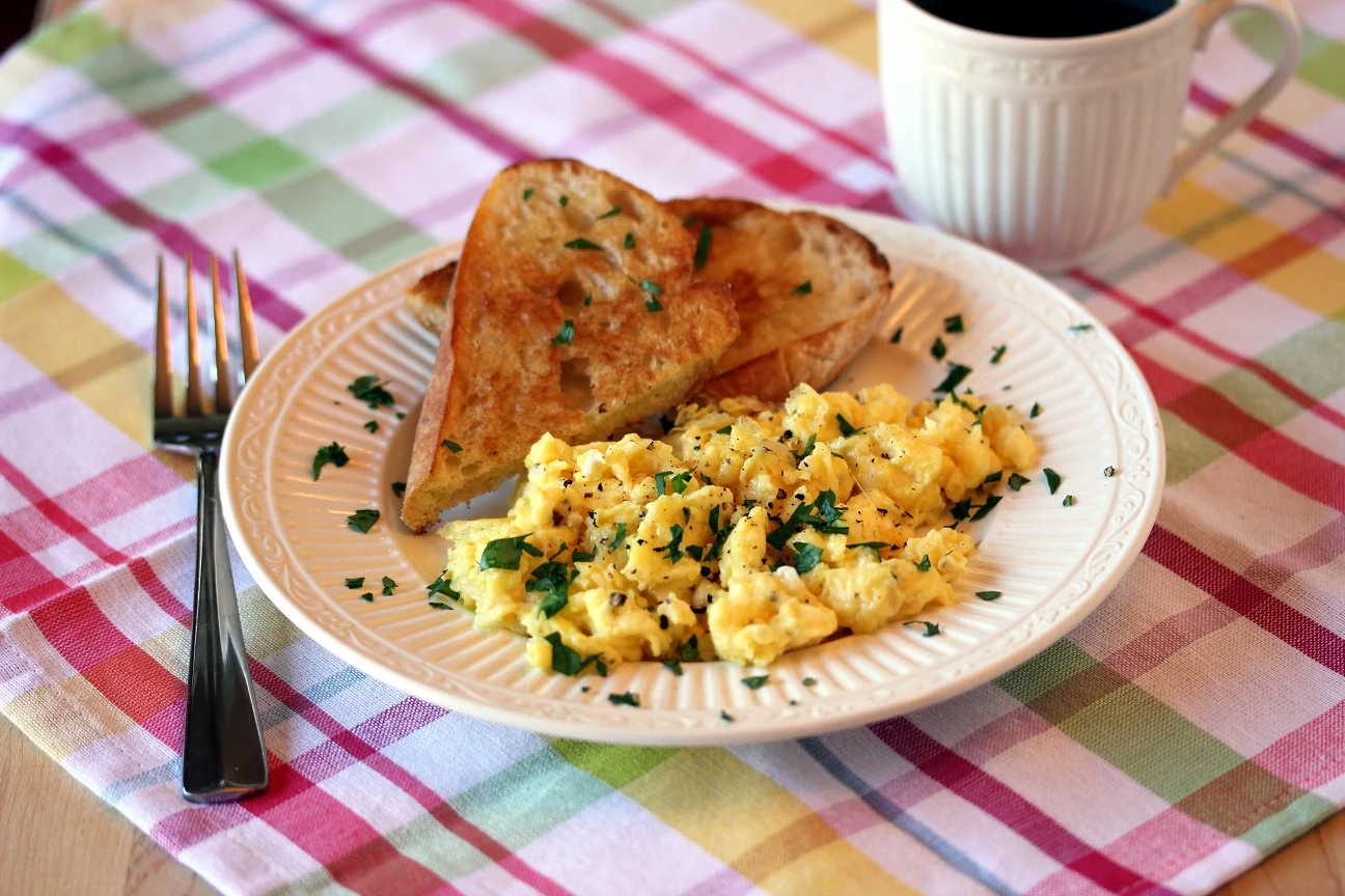Plated scrambled eggs with toast and coffee
