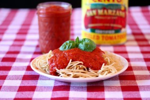 San marzano tomatoes over pasta with a jar of sauce and the tomato can in the background