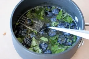Mashing the blueberries with a fork in the pot