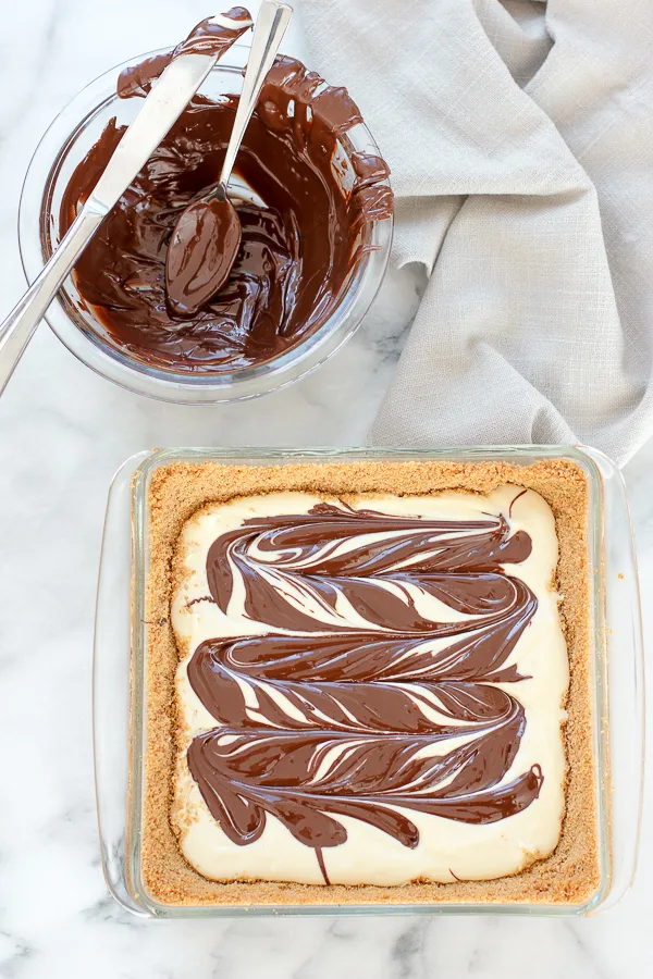 Process shot showing chocolate swirled into unbaked Chocolate Swirl Cheesecake Bars