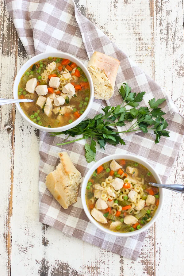 Lemon Dill Chicken Noodle Soup served in two soup bowls with crusty bread with a garnish of fresh parsley for visual appeal