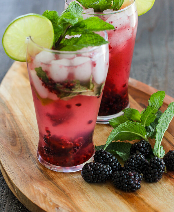 Two Blackberry Mint Spritzer Cocktail served in tall glasses and garnished with fresh lime and mint