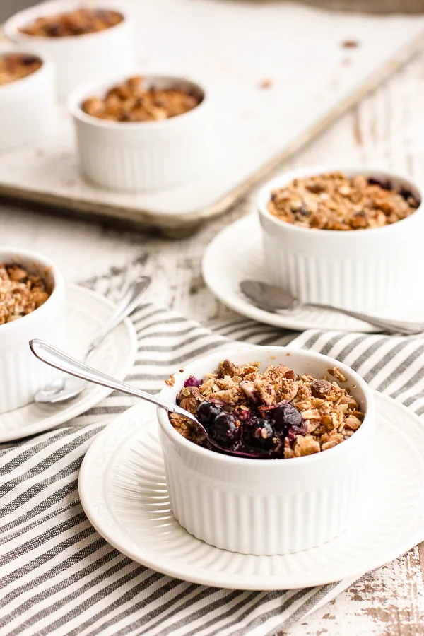 Showing a spoon in the White Chocolate Blueberry Crisp ramekin to take a bite out.