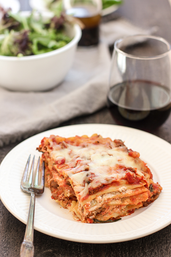 Traditional Lasagna slice plated and served with mixed greens and red wine
