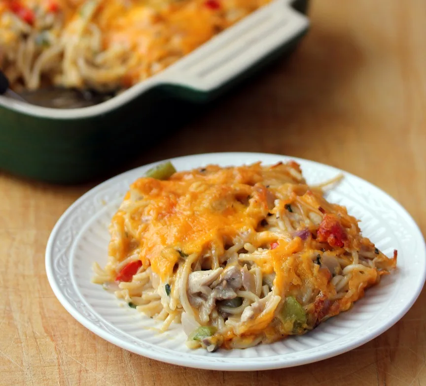 Chicken spaghetti casserole plated covered with melted cheddar cheese