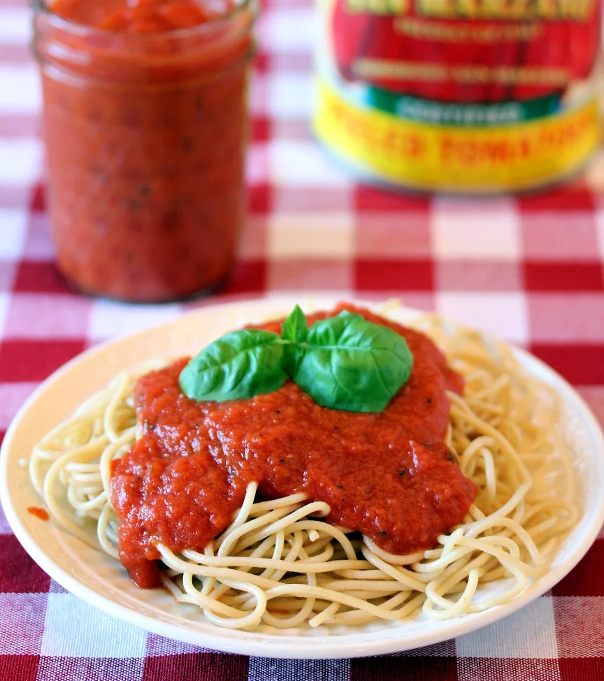 Spaghetti topped with san marzano pasta sauce with a jar of sauce and the can of tomatoes in the background