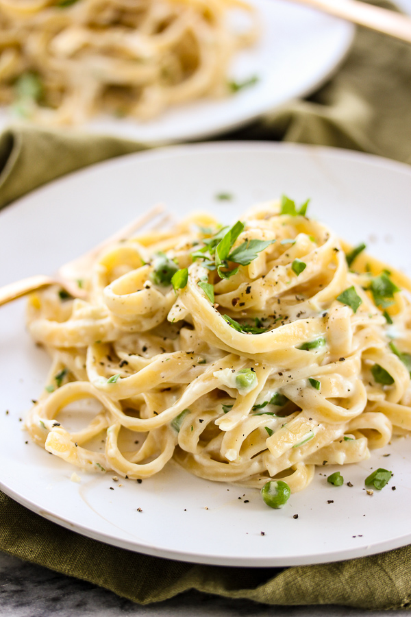 Skinny fettuccine plated and garnished with sweet peas and parsley