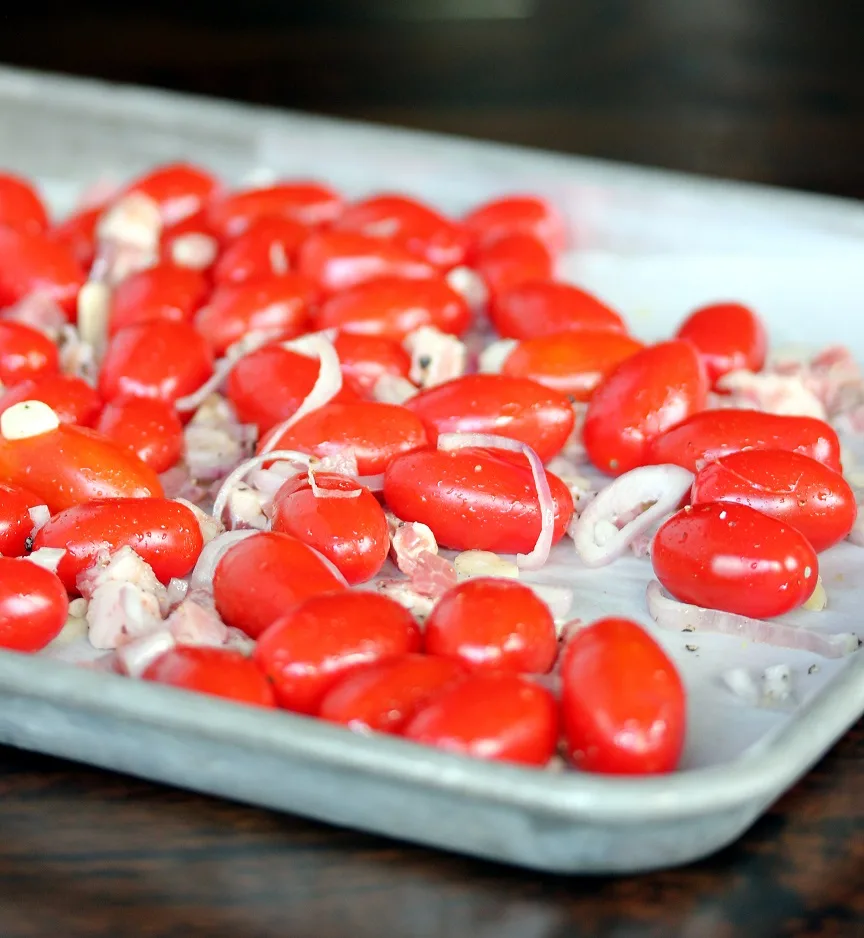 Grape tomatoes, shallots, garlic and pancetta on a baking sheet before roasting