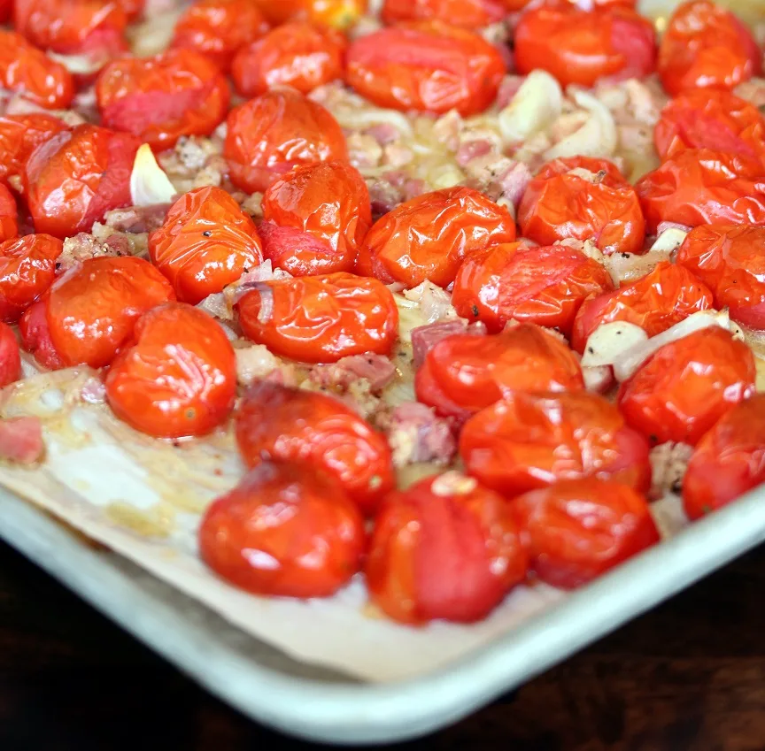 tomatoes, garlic, shallots and pancetta on baking sheet after being roasted