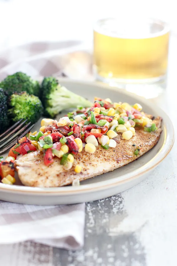 Close up photo of plated pan seared tilapia with spicy corn salsa and grilled broccoli