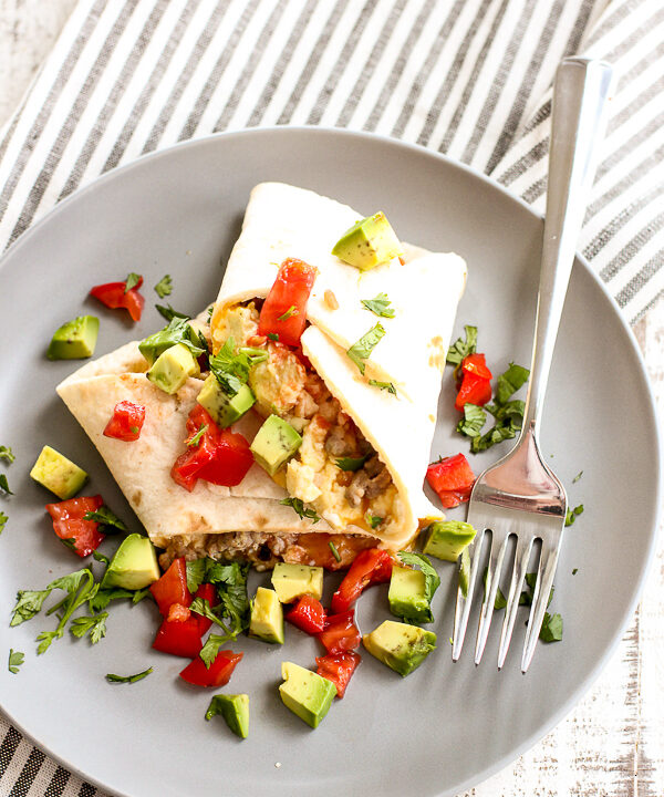 Make ahead low carb breakfast burrito plated with dices avocado, cilantro and tomato