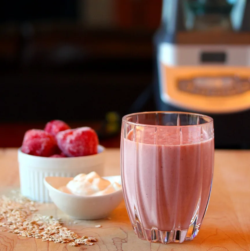 Oatmeal smoothie in a glass with berries and yogurt in the background